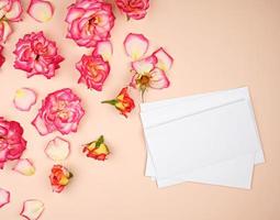 botões de rosa amarela e um envelope de papel branco em um fundo de pêssego foto