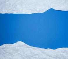 fundo azul com elementos de papel rasgado amassado branco, lugar para escrever op no meio foto