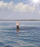 a mão do homem se projeta da água no meio do oceano foto