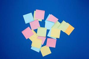 adesivos de papel em branco multicoloridos de cores diferentes em um fundo azul escuro foto