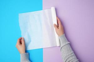 duas mãos femininas segurando um rolo de papel manteiga pergaminho branco foto