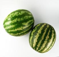 duas grandes melancias verdes listradas sobre um fundo branco foto