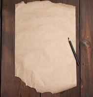 folha vazia rasgada de papel pardo e um lápis preto sobre uma superfície de madeira foto