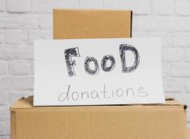 pilha de caixas de papelão e folha de papel branca com inscrição de doação de alimentos foto