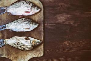 carpa de peixe na balança na tábua de cozinha foto