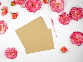 botões de rosa cor de rosa e um envelope de papel pardo foto