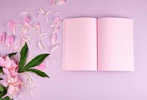 caderno em branco aberto com folhas cor de rosa e peônias florescendo foto