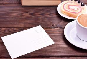 cartão de papel branco vazio sobre a mesa, xícara de café lateral foto