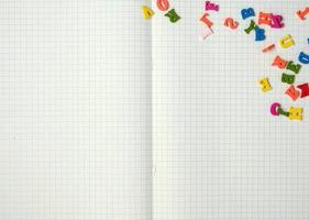 caderno aberto com folhas brancas em uma caixa e pequenas letras de madeira multicoloridas foto