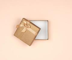 abra a caixa de presente dourada com um laço em um fundo bege foto