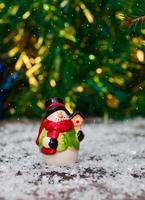 pequeno boneco de neve de cerâmica entre a neve foto