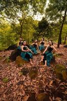 um grupo de mulheres asiáticas tira férias na floresta vestindo uma saia verde e sentada em uma pedra foto