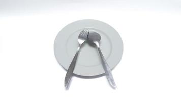 prato vazio com colher e garfo isolado no fundo branco foto