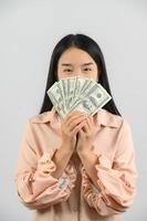 retrato de uma jovem alegre segurando notas de dinheiro e comemorando isolado sobre fundo branco foto