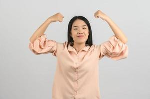 retrato de jovem mulher asiática na camisa rosa fazendo gesto forte isolado no fundo branco foto
