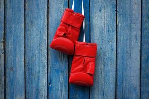 par de luvas vermelhas para kickboxing pendurado em uma corda branca foto