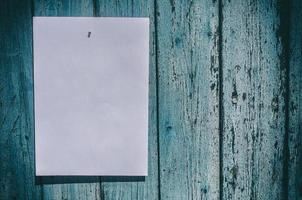 folha de papel branca pendurada em uma parede de madeira azul foto