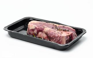 bife de carne crua de nova york é embalado em um recipiente de plástico e selado a vácuo foto