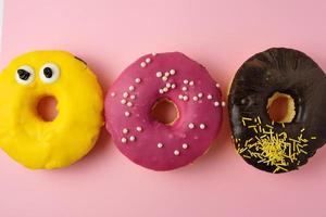 três donuts doces redondos diferentes com granulado em um fundo amarelo foto