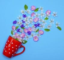 de caneca de cerâmica vermelha com bolinhas brancas derramadas flor aleatoriamente foto