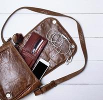 bolsa de couro marrom feminina aberta, um smartphone branco foto