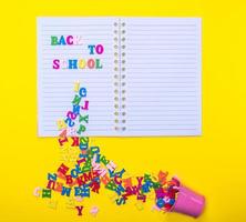 letras multicoloridas de madeira espalhadas de um balde de ferro em um notebook em uma linha foto