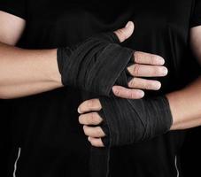 homem envolve as mãos em bandagem têxtil preta para esportes foto
