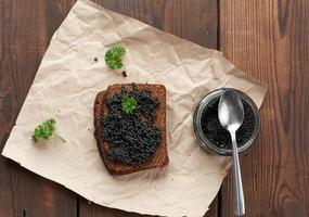 caviar paddlefish, uma fatia de pão e uma jarra em um pedaço de papel pardo, vista superior foto