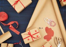 papel kraft marrom, sacolas de presente embaladas e amarradas com fita vermelha, coração vermelho, conjunto de itens para fazer presentes com as próprias mãos