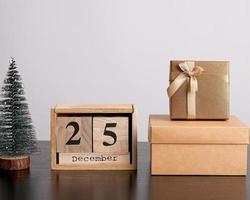 calendário retrô de madeira de blocos, árvore decorativa de natal e caixas de papelão com presentes foto
