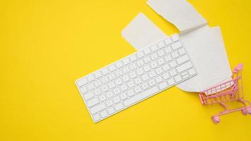 teclado sem fio branco, pilha de recibos de papel em fundo amarelo, conceito de análise de orçamento foto