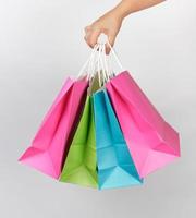 mão feminina segurando quatro sacolas de papel colorido para embalagens de compras foto