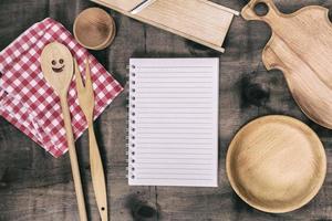 bloco de notas aberto com objetos de cozinha de madeira foto