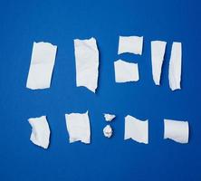 conjunto de vários pedaços de papel amassado branco rasgado sobre um fundo azul foto
