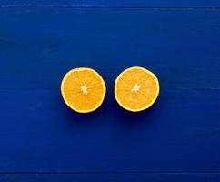 duas metades de uma laranja redonda sobre um fundo azul escuro de placas pintadas na cor azul tendência foto