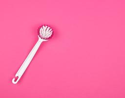 escova de cozinha com cabo de plástico branco sobre fundo rosa foto