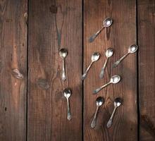 conjunto de pequenas colheres de chá de metal em uma mesa de madeira marrom, vista superior foto