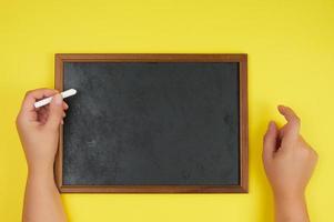 quadro de giz preto e duas mãos femininas com um pedaço de giz branco foto