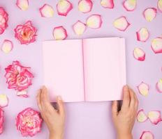 duas mãos femininas segurando um bloco de notas aberto com lençóis rosa limpos foto