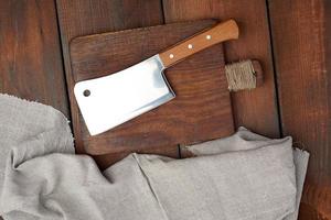 grande faca de carne afiada de aço encontra-se em uma placa retangular de madeira marrom foto