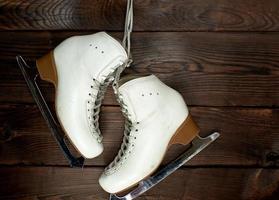 patins femininos de couro branco para patinação artística pendurados em um prego foto