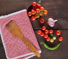 toalha de cozinha têxtil vermelha em uma gaiola e tomate cereja fresco foto