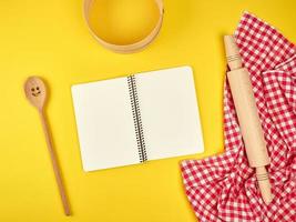 caderno aberto em branco e acessórios de cozinha de madeira foto