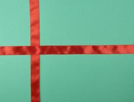 cruz de fita de cetim vermelha para cruzar no fundo verde foto