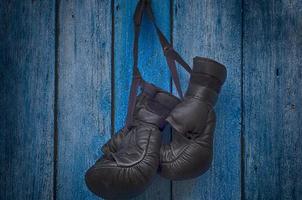 par de luvas pretas para boxe tailandês pendurado em um prego foto