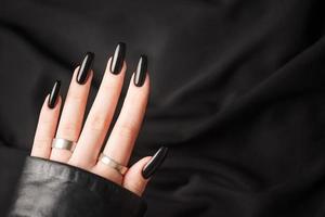 mãos de uma jovem com manicure preta nas unhas foto