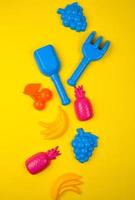 frutas multicoloridas de brinquedos de plástico em um fundo amarelo foto