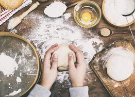 as mãos das mulheres seguram uma bola de massa de fermento em uma mesa foto