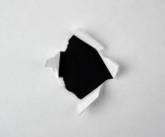 buraco rasgado redondo com bordas torcidas em papel branco foto