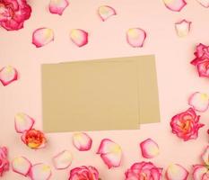 botões de rosa cor de rosa e envelope de papel pardo em um fundo bege foto